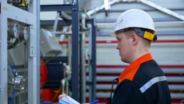 An Industrial Engineer Checks the Operation of Plant Equipment and Records Pressure and Temperature