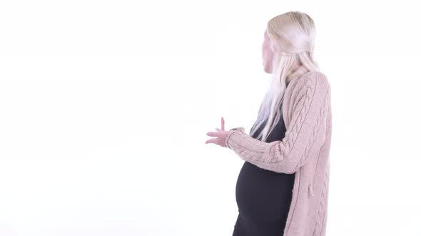 Happy Young Blonde Pregnant Woman Showing To the Back and Looking Excited