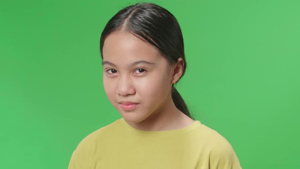 Terrible Asian Kid Girl Looking At Camera And Emotionally Flipping Something On Green Screen Studio