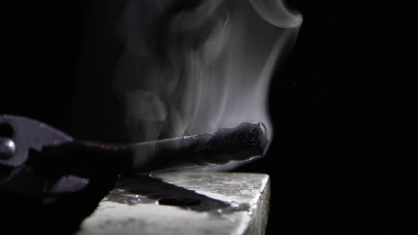 Piece of metal steaming being set on anvil.