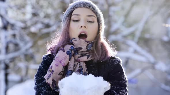 Happy Asian Woman Blowing Snow Raight to the Camera