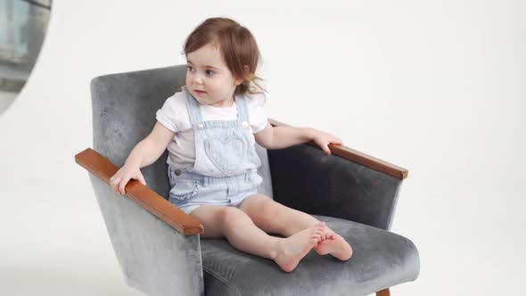Little Girl Sits in a Chair Starts to Move Gets Up and Leaves