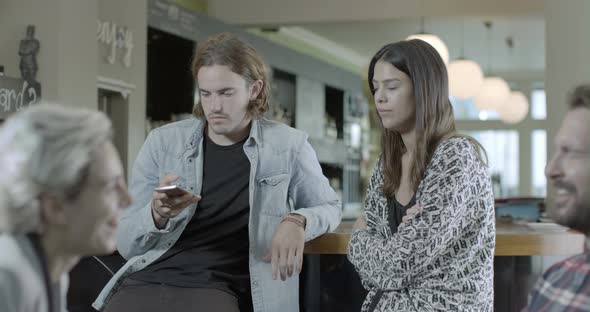 Man and woman taking self photograph with mobile phone while sitting in pub