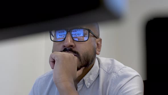 Close up abstract shot of a bored employee resting his chin on his clenched hand, his glasses creati