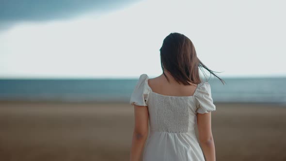 A cute Asian girl is walking on the beach by the sea