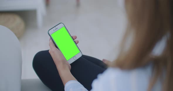 Woman Using and Looking Smart Phone Green Screen at Home. Young Girl Is Holding Smartphone With