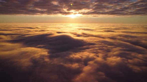 Cinematic footage of beautiful bright clouds in the sky with a setting sun on the background