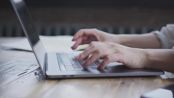 Closeup of Female Hands Typing Text on Laptop Keyboard in Light Modern Office