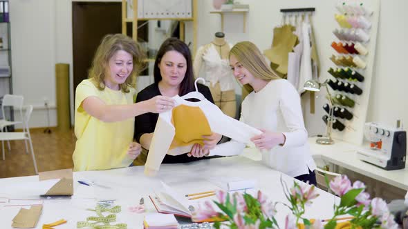 Shot of Three Fashion Designers Working and Deciding Details of New Collection of Clothes in the