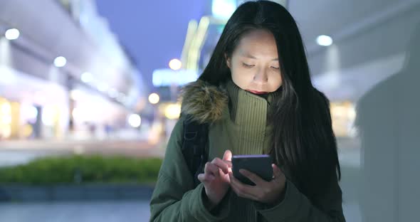 Woman using mobile phone in the city at night
