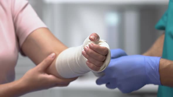 Physician Putting Elastic Bandage on Female Patient Arm, Joint Dislocation
