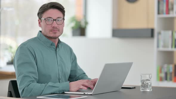 Middle Aged Man with Laptop Looking at Camera