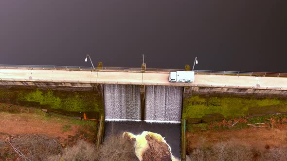 Aerial Birds Eye View Over Road On Encoro de Villasenin Reservoir And White Lorry Going Past