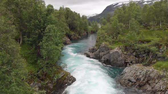 Beautiful river cascading down mountainside, aerial dolly view downstream