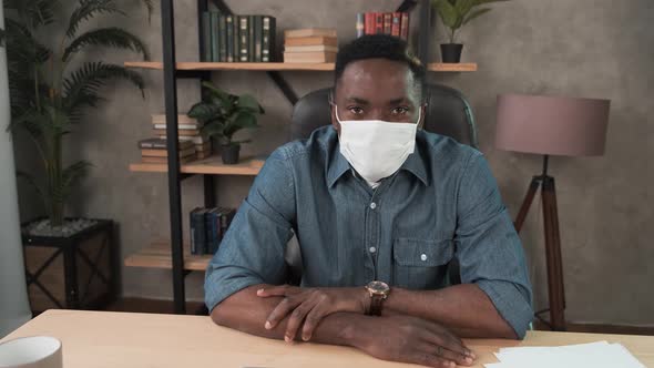 Confident Young African Businessman in Face Mask Office Workplace. Mixed Race Entrepreneur Talking
