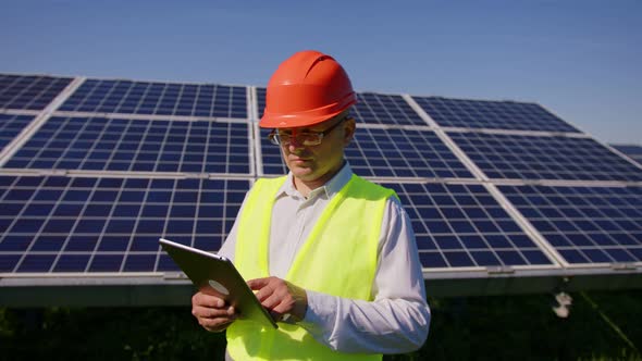 An Young Engineer is Checking with Tablet an Operation of Sun and Cleanliness on Field of