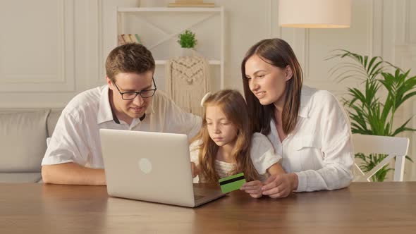 . Parents With Child Use a Credit Card for Online Shopping, Buying By the Internet