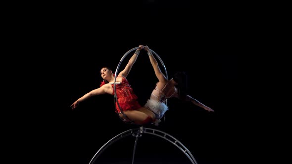 Two Flexible Gymnasts Performs a Trick on the Aerial Hoop Metal Construction