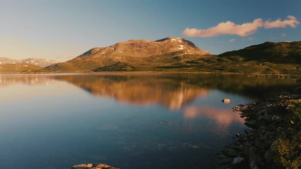 The beautiful morning light over the Norwegian mountains and lake - low aerial