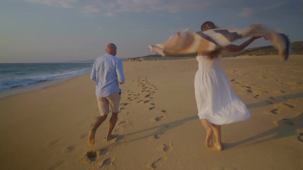 Back View of Couple Running on Sandy Beach