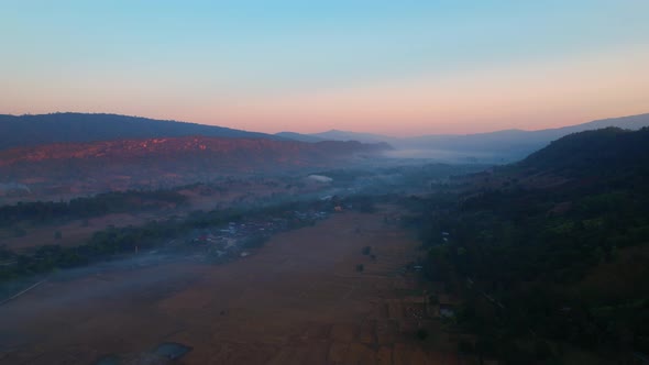 Aerial view over villages and barren fields in countryside during sunrise