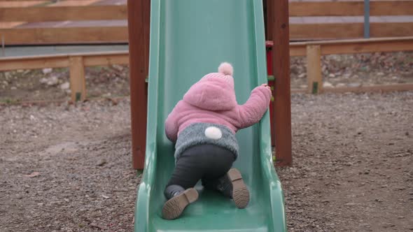 Toddler Girl Trying to Climb the Children's Slide at Local Playground