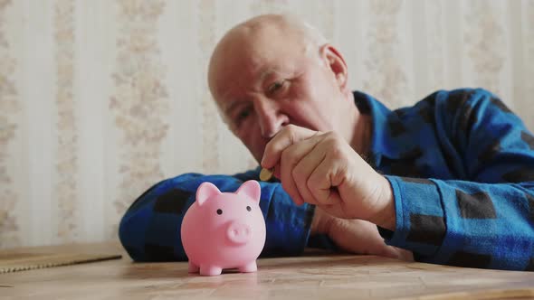 Senior Caucasian Man Putting Coin Into the Piggy Bank Savings Concept