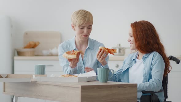 Little Paralyzed Girl in Wheelchair Having Lunch with Mother Eating Tea and Pizza Enjoying Food