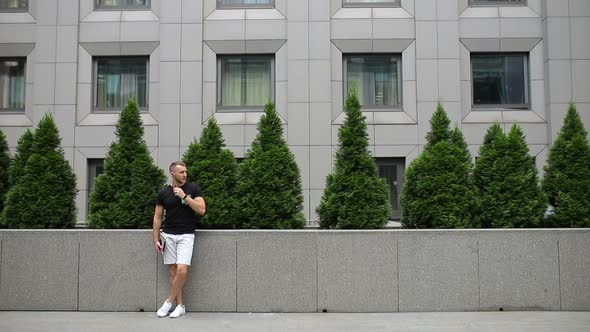 The guy on the street listens to music with a tablet in his hands