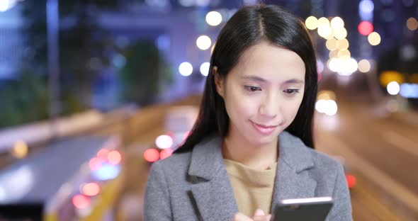 Woman look at mobile phone in city at night