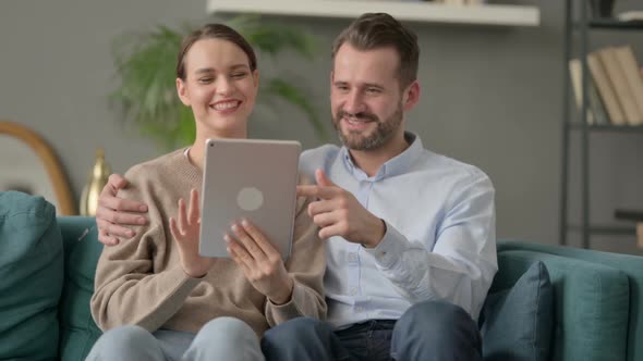 Couple Using Tablet While Sitting on Sofa