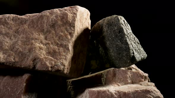 Pieces of Solid Rough Granite Stone Rotating Against a Black Studio Background