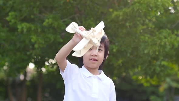 Cute Asian Child Playing Wooden Airplane In The Park Outdoors