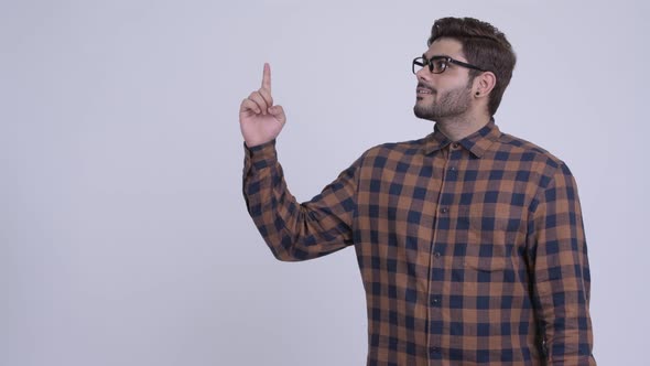 Happy Young Bearded Indian Hipster Man Thinking While Pointing Up