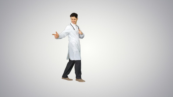 Young doctor wearing lab coat dancing on gradient background