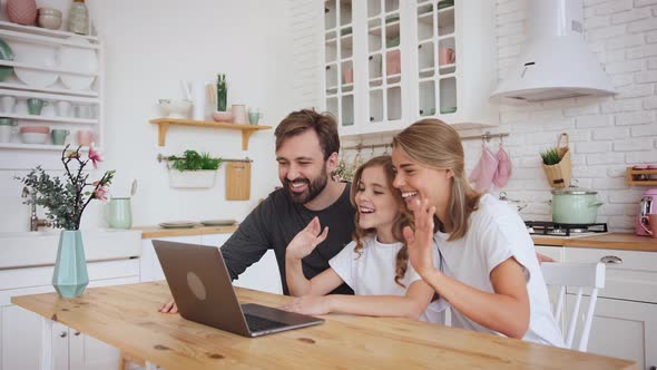 Happy Positive Family Young Parents Couple and Cute Little Daughter Using Laptop Computer for a