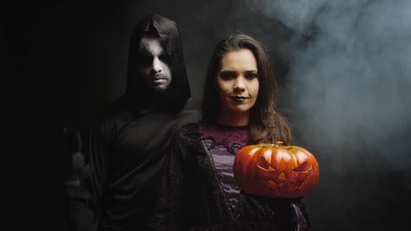 Young Woman Dressed Up Like a Witch Next to a Dark Grim Reaper