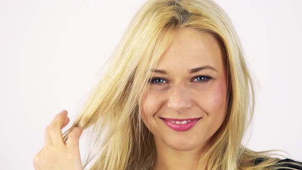 A Young Attractive Woman Smiles at the Camera and Plays with Her Hair - White Screen Studio