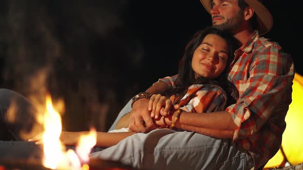 Man Hugging Woman in Front of the Bonfire on Beach Party in the Dark