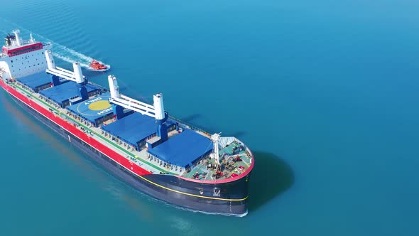 AERIAL VIEW: Flying Over Massive Ship Filled Moving in the Quiet Sea. Cargo Being Moved By Large