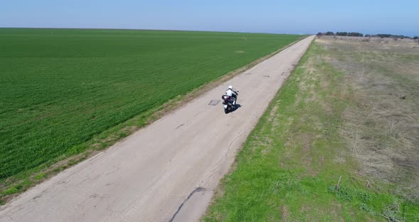 Aerial drone shot of biker rides a motorcycle on the old road