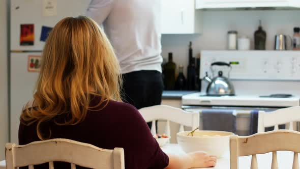 Man serving breakfast to woman in kitchen