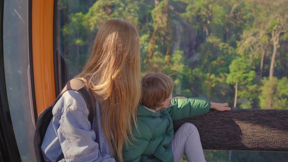 A Woman and Her Son Ride in a Cable Car Up the Mountain to the Ba Na Hills Resort in the City of