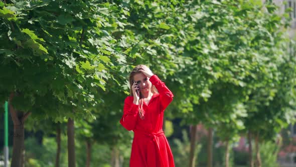 Woman using smartphone outdoors. Happy young woman talking on phone while walking on the street