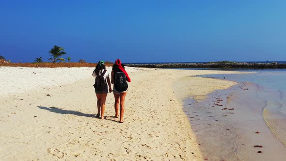 Modern fun women travelling spending quality time at the beach on summer white sand and blue 4K back