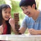 Asian girl playing a game of risk trying to move wooden blocks with father. - VideoHive Item for Sale