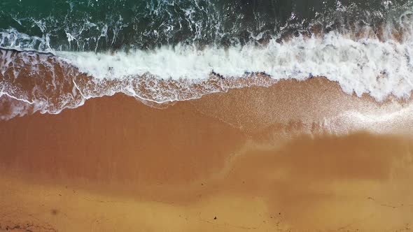 Ocean waves splashing and foaming on beautiful brown unspoiled sand of exotic beach, beautiful shore