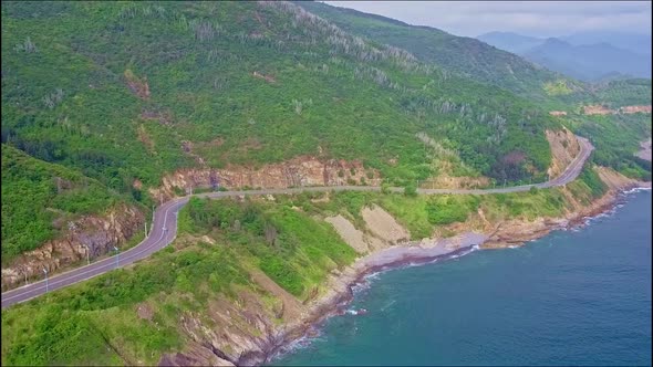 Drone Flies Above Highway Running Along Green Sea Coast