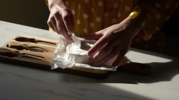 Female in yellow polka dot shirt with a cheese on table in kitchen