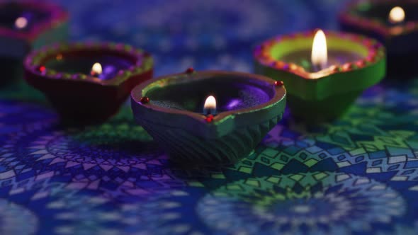 Lit candles in decorative clay pots on patterned table top, blown out, focus on foreground